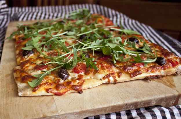 Pizza de tomàquets, olives negres i ruca